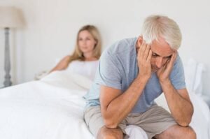 A couple sitting on a Bed, looking distressed, representing the emotional impact of sexual dysfunction